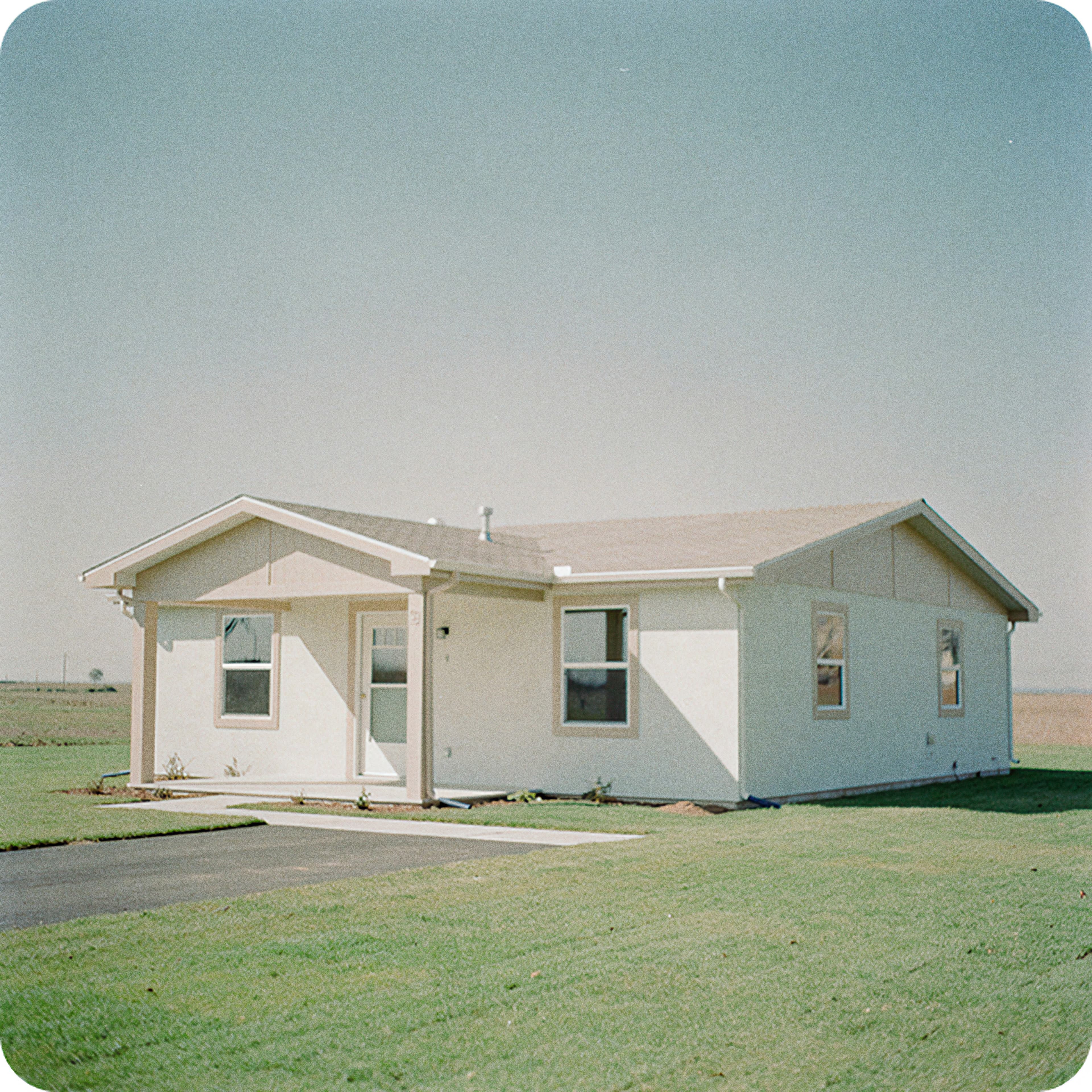 Single-storey house on a green lawn, representing real estate